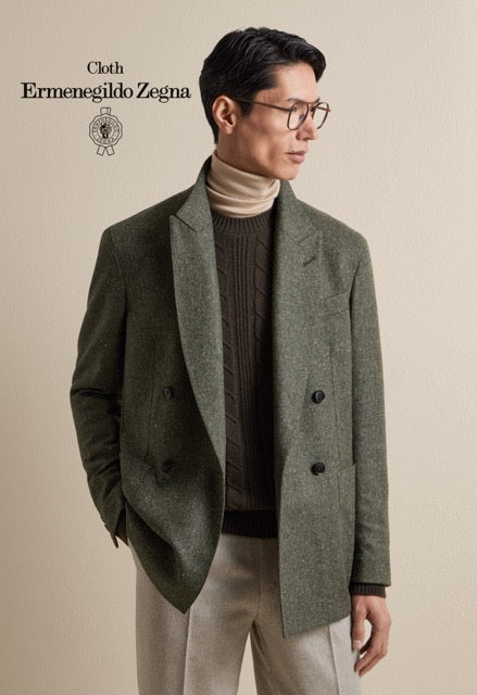 Model wearing an olive green double-breasted jacket, brown knitwear and beige trousers; Ermenegildo Zegna cloth reference 67006.