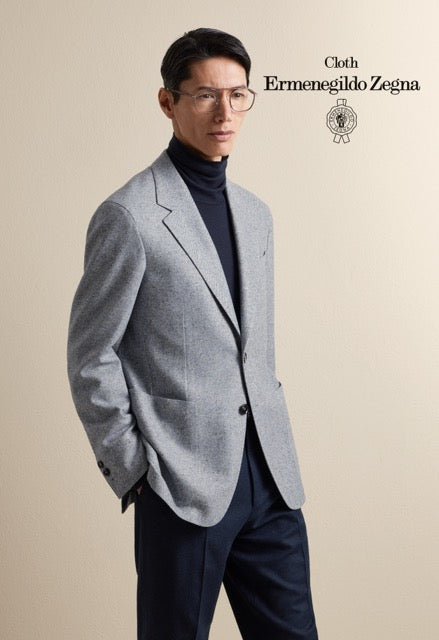 Model wearing a light grey single-breasted jacket over a navy turtleneck and trousers; Ermenegildo Zegna cloth reference 67009.