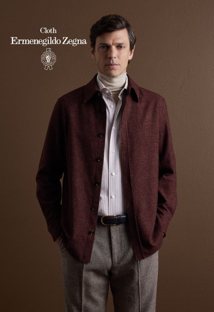 Model wearing a burgundy overshirt over a striped shirt, white turtleneck and grey trousers; Ermenegildo Zegna cloth reference 67026.