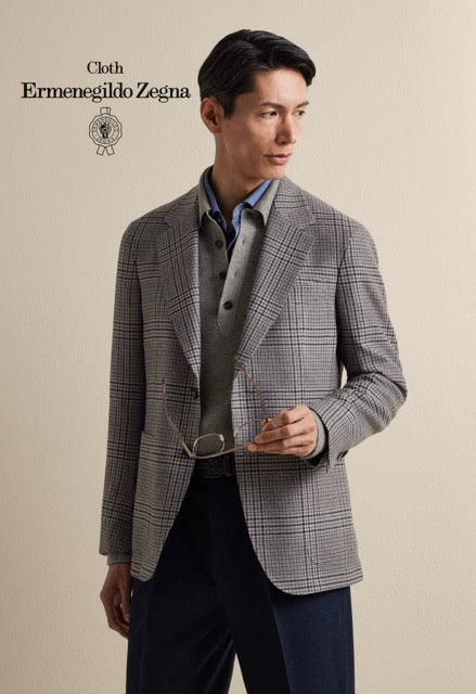 Model wearing a grey glen check jacket over layered shirts with navy trousers; Ermenegildo Zegna cloth reference 67034.