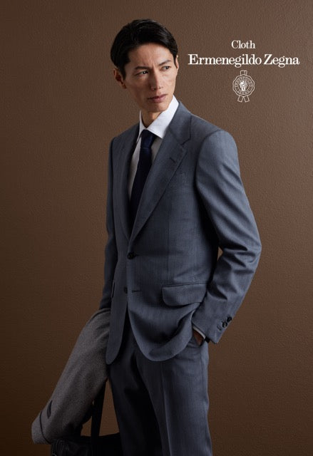 Model wearing a blue-grey single-breasted suit, white shirt and navy tie; Ermenegildo Zegna cloth reference 67062.
