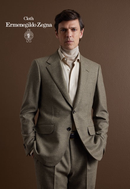 Model wearing a taupe fine-check suit over cream layered knitwear and a shirt; Ermenegildo Zegna cloth reference 67065.