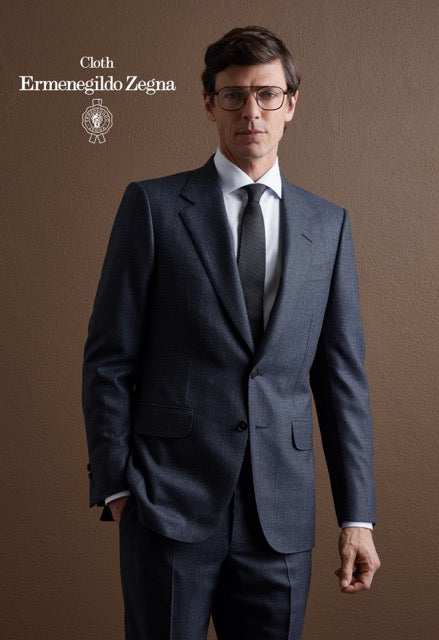 Model wearing a navy single-breasted suit, white shirt and grey tie; Ermenegildo Zegna cloth reference 67079.