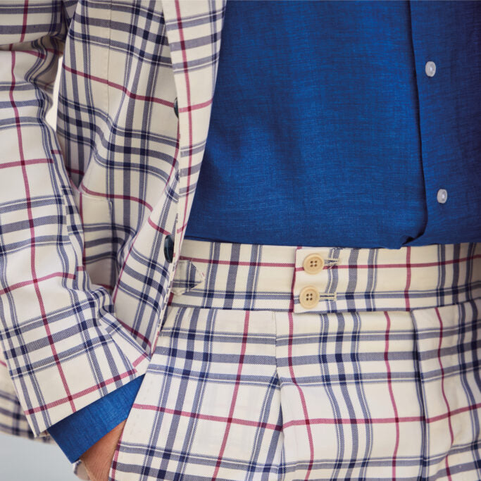 Close-up of an ivory windowpane suit crafted from Ariston Italian fabric, featuring bold navy and burgundy overcheck, paired with a cobalt blue dress shirt and refined tailoring.