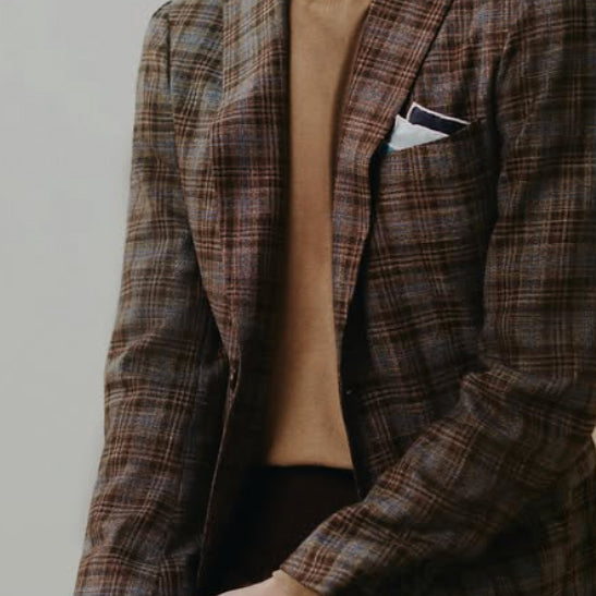 Brown plaid sport coat crafted from Dormeuil luxury fabric, styled with a camel knit sweater and white pocket square for refined casual tailoring.
