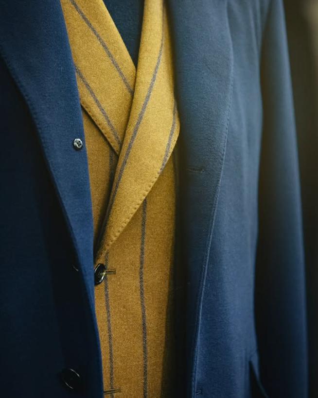 Close-up of a mustard yellow striped jacket layered beneath a navy coat.