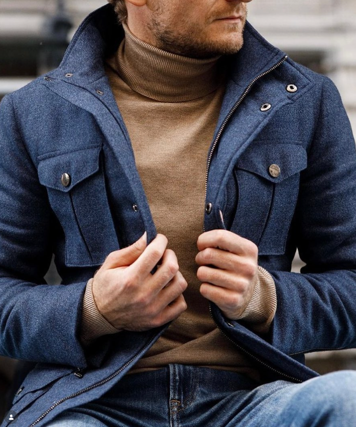 Navy field jacket with flap pockets worn over a camel turtleneck.