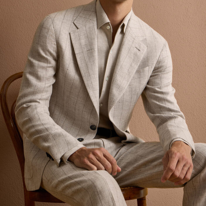 Man wearing a light beige custom suit made from Ermenegildo Zegna Italian fabric, showcasing refined tailoring and modern luxury.