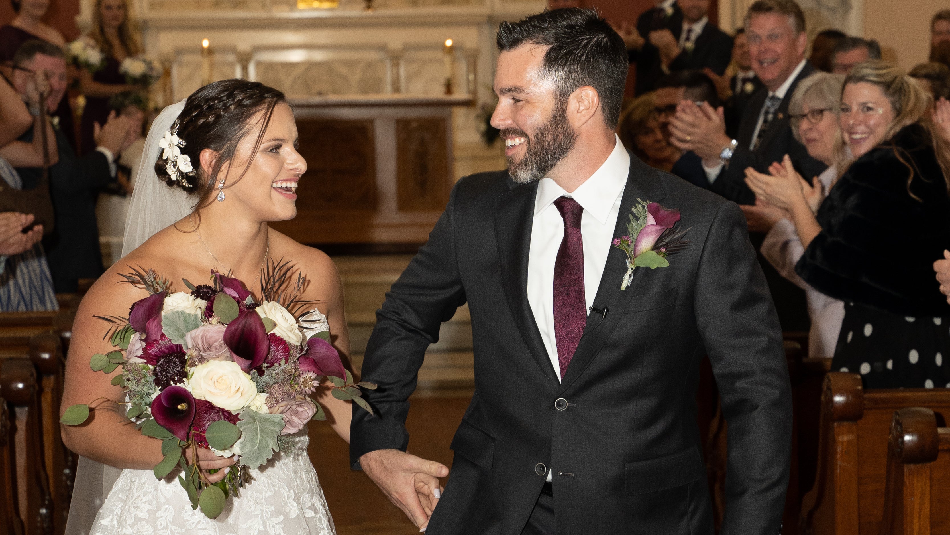 Bride and groom walking down the aisle after their wedding ceremony, with the groom wearing a custom charcoal suit by Jeffrey Bartlett Clothiers.