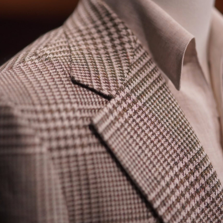 Close-up of a brown Glen plaid jacket crafted from Lanificio Cerruti Italian fabric, highlighting the refined pattern, sharp peak lapel, and exceptional tailoring.