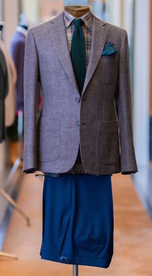 Light gray sport coat crafted from Lanificio Cerruti Italian fabric, styled with a plaid dress shirt, green tie, and blue trousers to showcase refined contemporary tailoring.