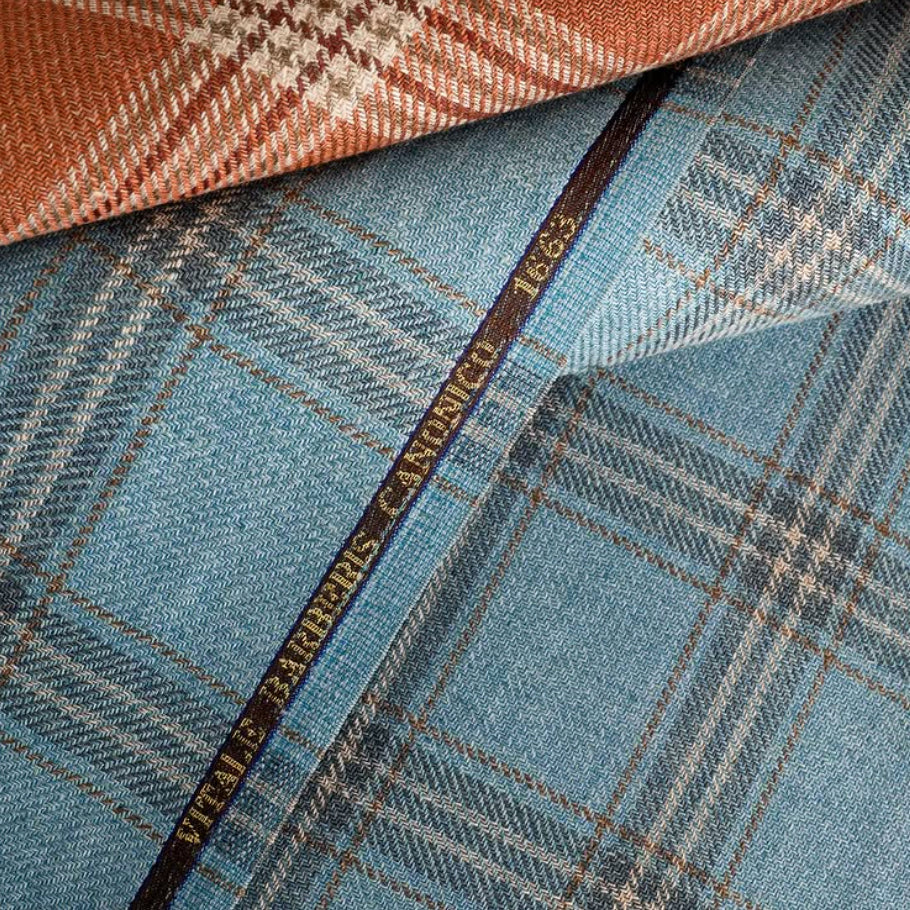 Layered blue herringbone and rust plaid wool fabrics from Vitale Barberis Canonico, highlighting refined Italian weaving, rich texture, and timeless textile design.
