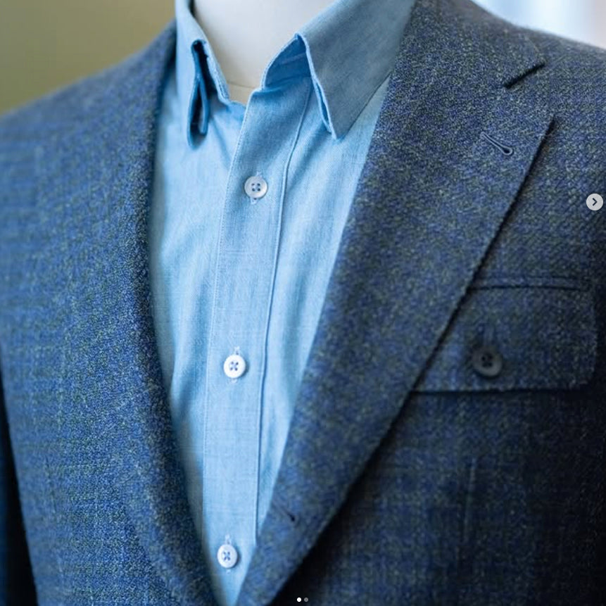 Close-up of a blue herringbone sport coat crafted from Lanificio Cerruti Italian fabric, showcasing soft texture, hand-finished tailoring, and a crisp white dress shirt.
